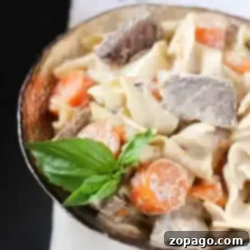 A bowl of creamy pasta with tender stew meat and carrots, resembling an Instant Pot beef stroganoff, garnished with fresh basil leaves.