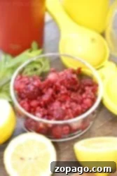 Bowl of crushed raspberries and fresh lemons ready for the juicer, perfect for crafting homemade raspberry lemonade on a rustic wooden surface.