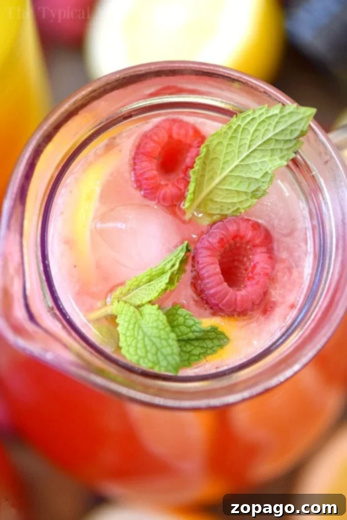 This homemade raspberry lemonade recipe only requires 4 ingredients and is perfect for Summertime! Packed with fresh fruit it's my favorite on the go drink. #homemade #raspberry #lemonade #drink #juice Glasses filled with homemade raspberry lemonade, fresh mint, ice, and lemon slices, ready to be served.