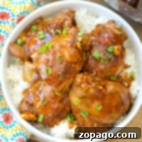 A bowl of white rice topped with Instant Pot spicy teriyaki chicken thighs and chopped green onions.