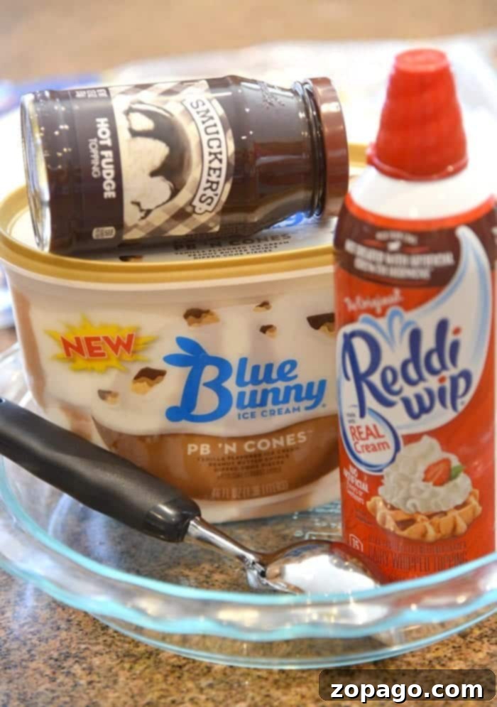 This easy layered ice cream sundae pie is incredible! Layers of fudge and ice cream topped with whipped cream and sprinkles makes it a fun birthday dessert. A completed layered ice cream sundae pie, ready to be frozen and served.