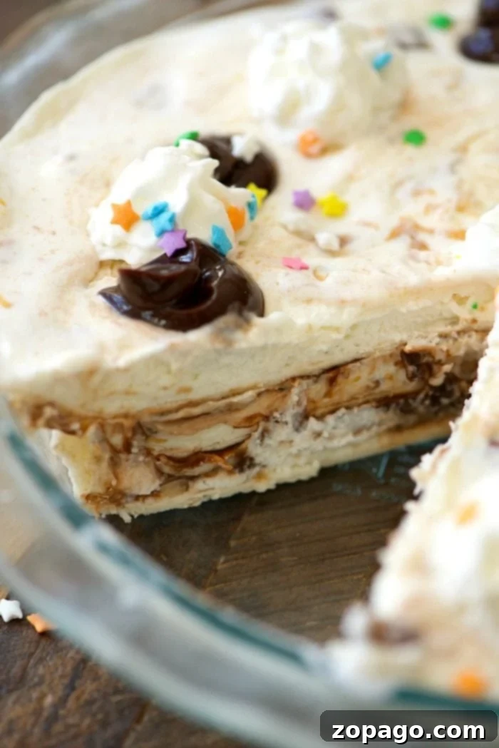 This easy layered ice cream sundae pie is incredible! Layers of fudge and ice cream topped with whipped cream and sprinkles makes it a fun birthday dessert. The easy ice cream sundae pie being assembled, showing layers of ice cream and fudge.