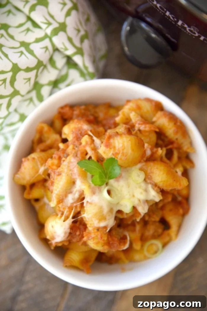 Lazy Crockpot lasagna casserole is packed with all the flavors of traditional lasagna but much easier to make! No boiling the noodles required, just dump it all in your slow cooker and when you're ready it's the perfect dinner casserole your whole family will love for sure. #lasagna #casserole #crockpot #slowcooker #thetypicalmom #crockpotrecipes #crockpotlasagna Delicious crockpot lasagna casserole, brimming with cheesy goodness and rich sauce, is shown served directly from the slow cooker, highlighting its convenience and appeal as a family dinner.