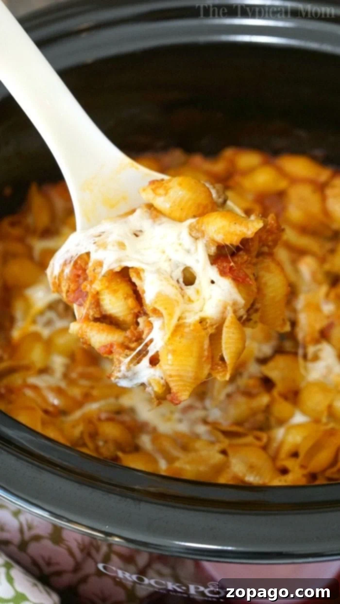 Crockpot lasagna casserole is packed with all the flavors of traditional lasagna but so much easier to make! No boiling the noodles required, just dump it all in your slow cooker and when you're ready it's the perfect dinner casserole your whole family will love for sure. #lasagna #casserole #crockpot #slowcooker #thetypicalmom #crockpotrecipes #crockpotlasagna A generous spoonful of cheesy pasta and rich sauce is carefully lifted from a crockpot lasagna, revealing the comforting layers and textures within, ready to be enjoyed.