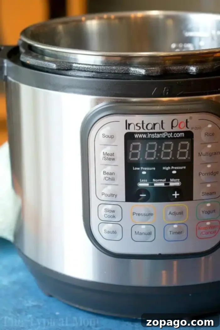 How to use an Instant Pot instructions are here + I have some easy Instant Pot recipes for you to try! #instantpot #pressurecooker #beginners #buttons #instructions #instantpotrecipes #thetypicalmom #instantpotinstructions The Instant Pot's sleek digital display, currently turned off, invites exploration of its versatile settings for soup, meat/stew, and beans/chili. Resting on a blue surface with a touch of green cloth beside it, this image sparks curiosity about how to use an Instant Pot effectively.