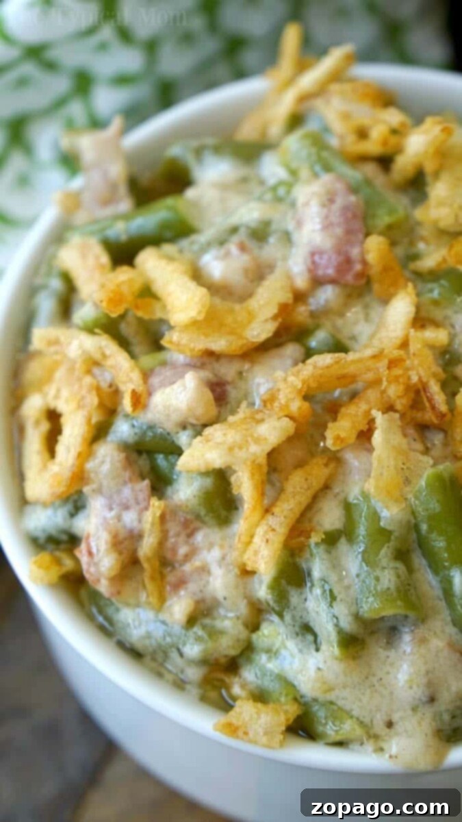 Quick Green Bean Casserole 6 Close-up of an instant pot green bean casserole, topped with crispy fried onions, served in a white bowl.