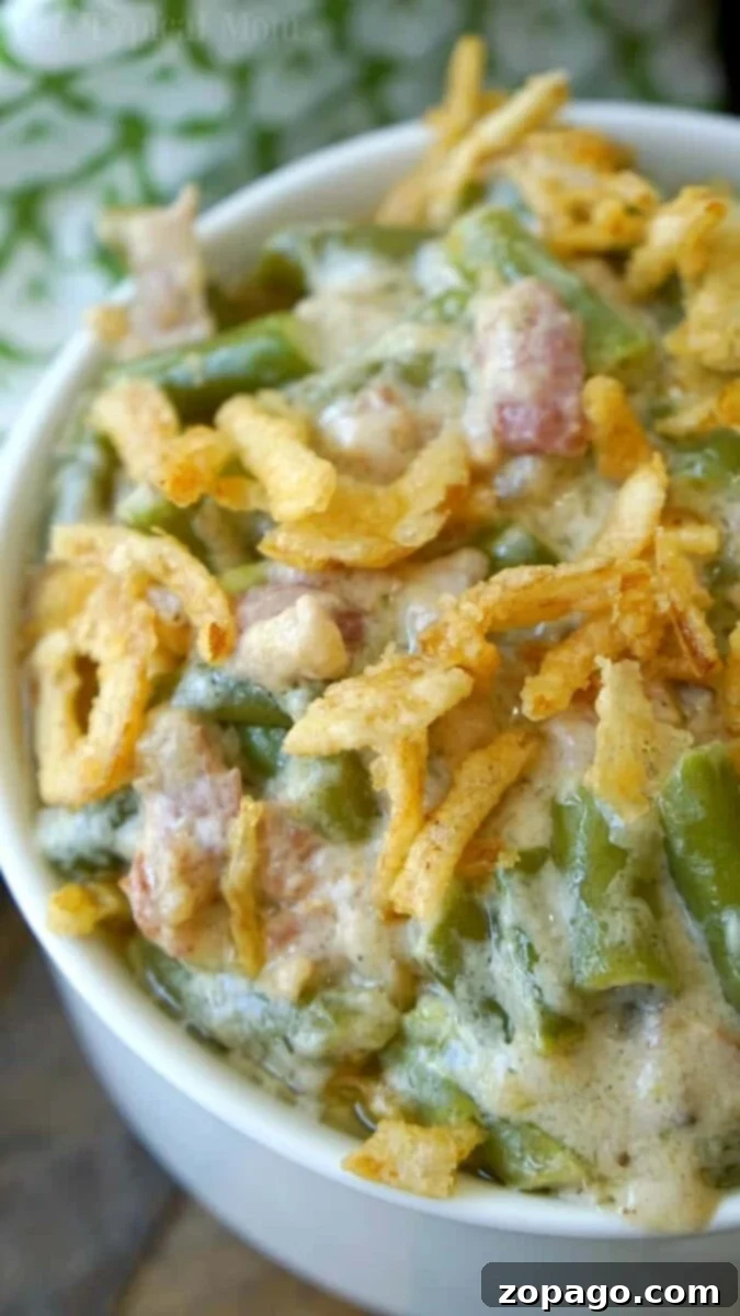 Ninja Foodi green bean casserole with bacon and crispy fried onions is a flavorful and easy-to-make side. Prepare a double batch for holiday gatherings or family dinners. #instantpot #pressurecooker #greenbeancasserole #sidedish #greenbeans Close-up of an Instant Pot green bean casserole, topped with crispy fried onions, served in a white bowl, ready for the holidays.