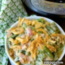 Creamy Instant Pot Green Bean Casserole 3 A bowl of Instant Pot green bean casserole topped with crispy onions, with a pressure cooker in the background.