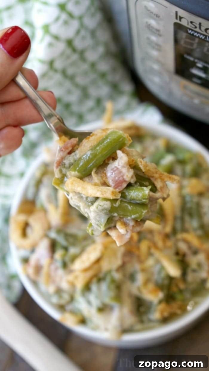 Pressure cooker green bean casserole with bacon and crispy fried onions is an amazing side dish. Make a double batch for your next gathering! #instantpot #pressurecooker #greenbeancasserole #sidedish #greenbeans Instant Pot green bean casserole with bacon, served in a casserole dish with crispy onions on top.