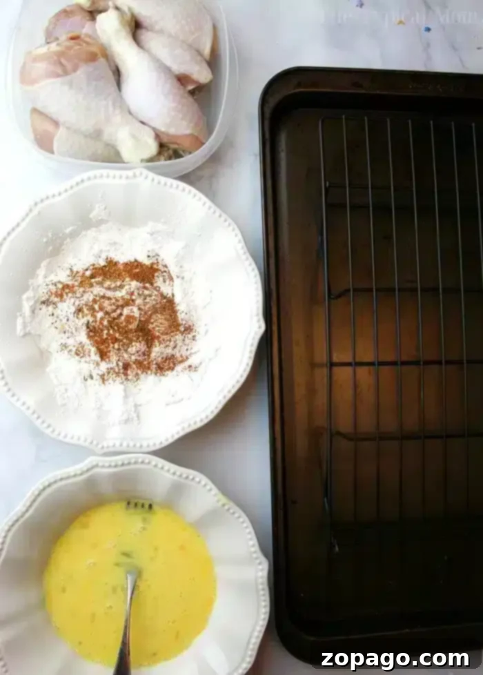Easy copycat Kentucky Fried Chicken recipe for the crispiest chicken ever. Juicy chicken drumsticks fried quickly then baked to perfection & so flavorful. #kfc #kentuckyfriedchicken #copycat #friedchicken Ingredients for Copycat Kentucky Fried Chicken: raw drumsticks, seasoned flour, beaten eggs, and an empty baking rack.