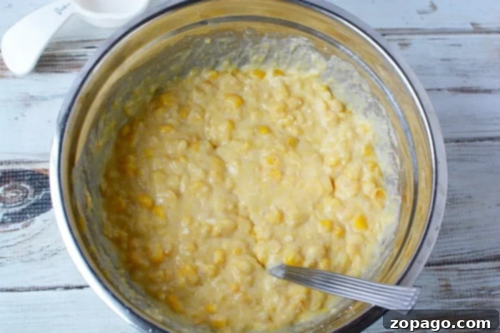 Easy Crockpot Corn Casserole 5 A serving of moist and creamy corn casserole, garnished with fresh herbs, ready to be enjoyed.