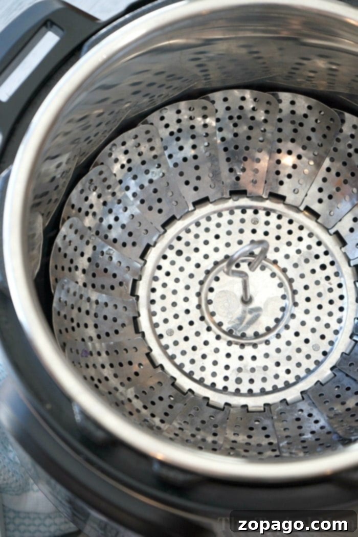 Velvety Instant Pot Cauliflower 6 A stainless steel Instant Pot vegetable steamer basket, filled with perfectly steamed cauliflower florets, ready for mashing.