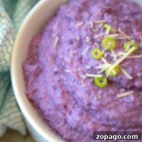 Creamy purple mashed cauliflower in a bowl, garnished with sliced green onions and grated cheese, resembling the smooth texture of an instant pot cauliflower mash.