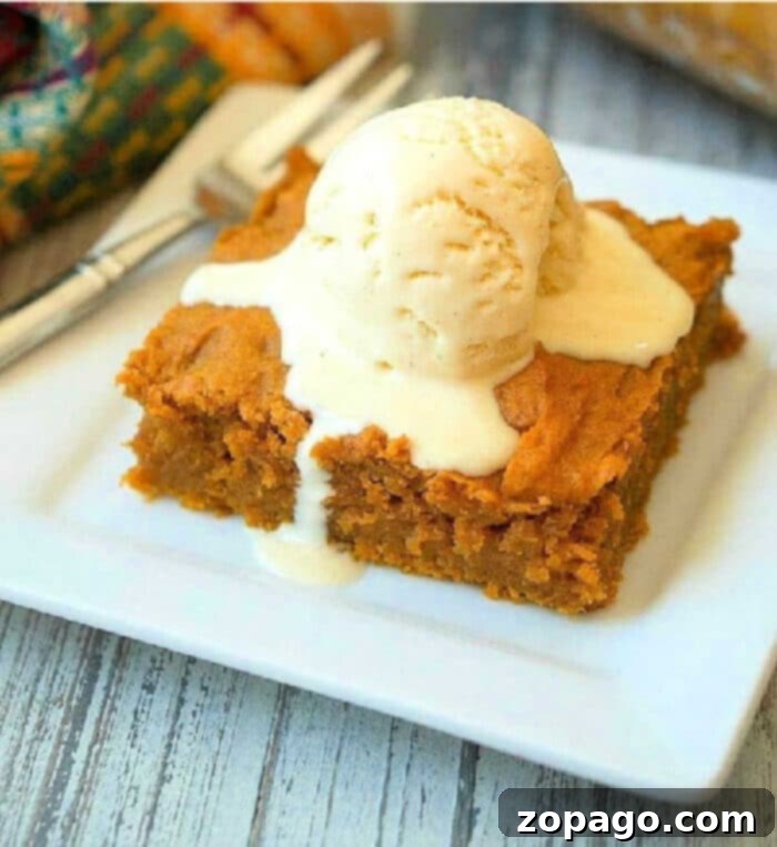 Effortless Pumpkin Pudding Cake 2 A slice of pumpkin pudding cake recipe is topped with a scoop of melting vanilla ice cream on a white plate, highlighting its moist texture.