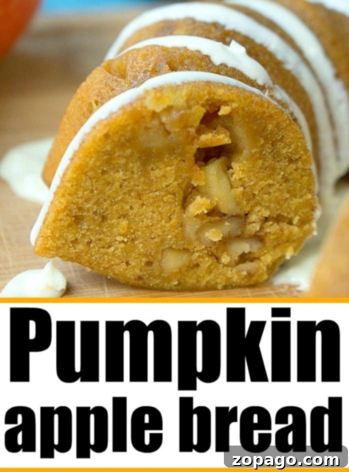 Pumpkin apple bread is a perfect breakfast or dessert for Fall! Moist pumpkin bread packed with diced apples and nuts is our favorite treat. #pumpkin #apple #bread #pumpkinrecipes #pumpkinapple A top-down view of a freshly baked pumpkin apple bread loaf, garnished with chopped walnuts, on a light background.