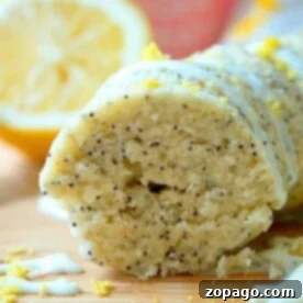 Close-up of sliced instant pot lemon poppy seed cake with glaze and lemon zest on top. Lemon slice in the background.