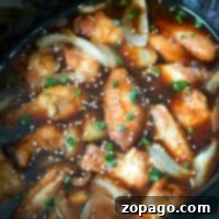 Slow cooker teriyaki chicken wings simmer in sauce with sliced onions, then are topped with sesame seeds and chopped green onions for a flavorful finish.