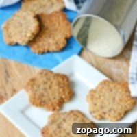 Four homemade hazelnut cookies rest on a white plate, with more cookies and a sugar canister in the background.
