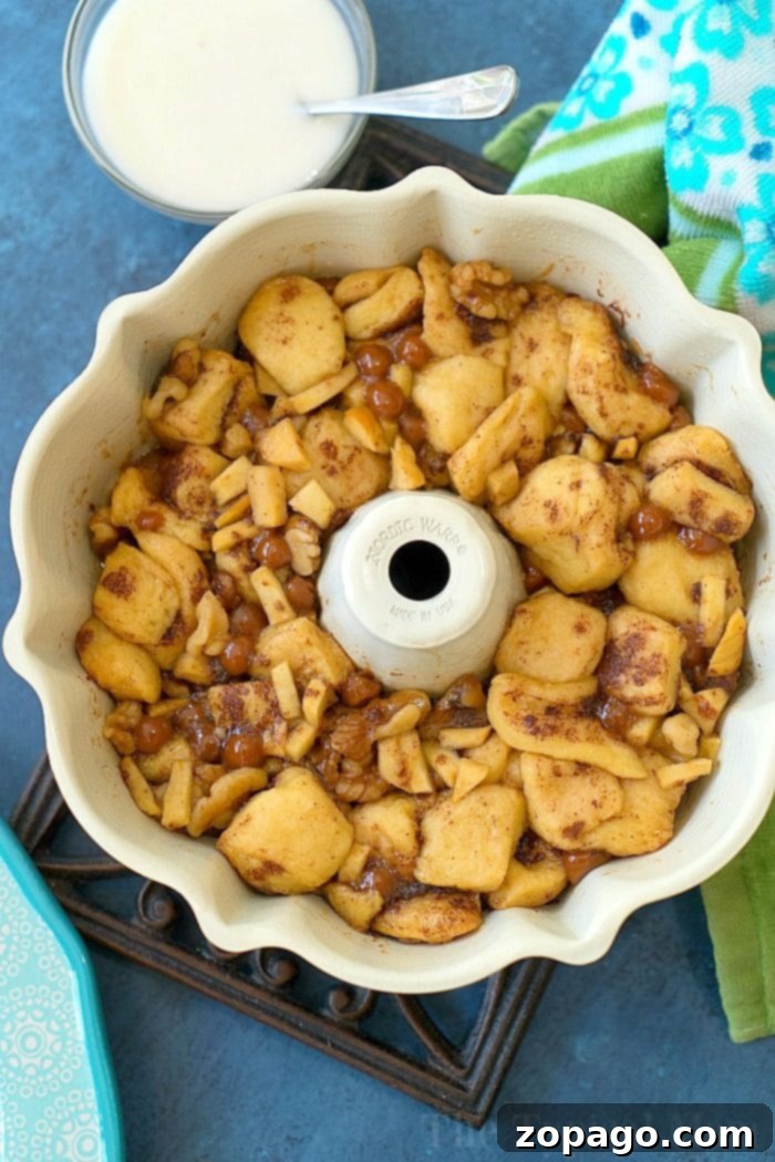 Instant Pot caramel apple monkey bread is so addicting and easy to make with ready made cinnamon rolls! If it's hot and you're not about to turn on your oven this is the new way to bake! #instantpot #pressurecooker #monkeybread #dessert #instantpotrecipes #thetypicalmom #cinnamonroll A top-down view of Instant Pot caramel apple monkey bread, generously drizzled with white icing, sitting on a wooden board.