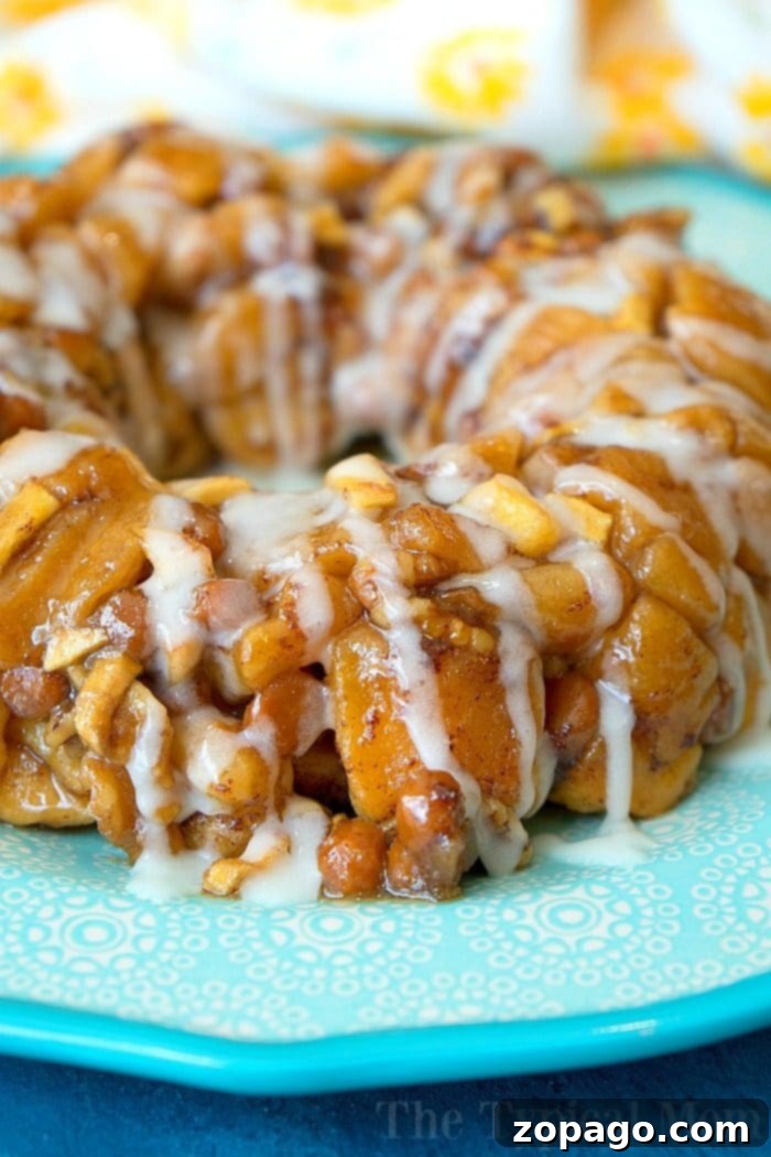 Instant Pot caramel apple monkey bread is so addicting and easy to make with ready made cinnamon rolls! If it's hot and you're not about to turn on your oven this is the new way to bake! #instantpot #pressurecooker #monkeybread #dessert #instantpotrecipes #thetypicalmom #cinnamonroll A large serving of Instant Pot caramel apple monkey bread, gooey and ready to eat, topped with icing.