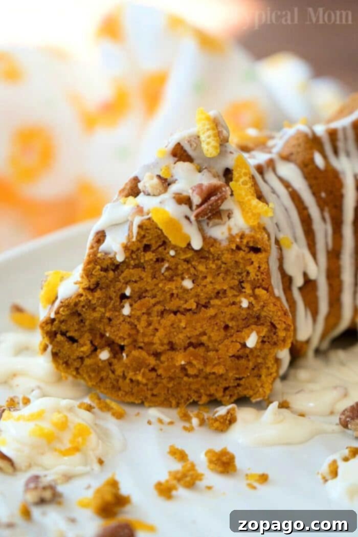 Spiced Gingerbread Pumpkin Bundt 2 Slice of moist gingerbread pumpkin bundt cake with frosting, pecans, and orange zest on a festive plate.