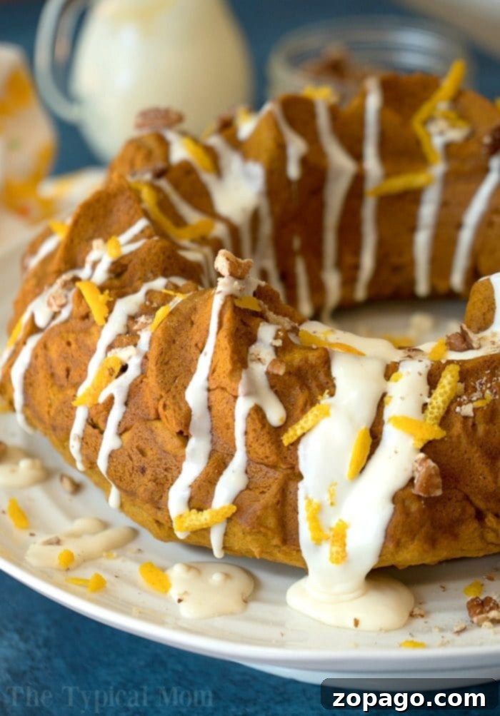 A stunning gingerbread pumpkin bundt cake, perfectly baked and garnished, ready to impress at any festive occasion. Full view of a beautifully decorated gingerbread pumpkin bundt cake on a serving plate, ready for a holiday celebration.