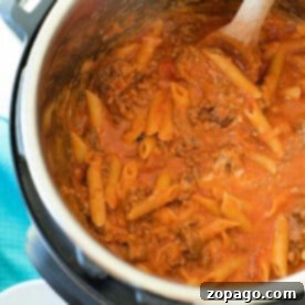 Pasta with meat sauce being stirred with a wooden spoon inside an Instant Pot for a delicious pressure cooker lasagna casserole.