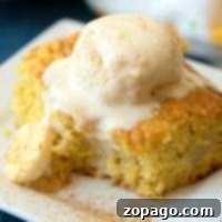 A slice of banana cake topped with a scoop of vanilla ice cream rests elegantly on a white square plate, evoking the comforting flavors of banana pudding.
