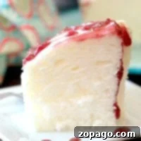 A perfect slice of Instant Pot angel food cake adorned with strawberry glaze on a pristine white plate.