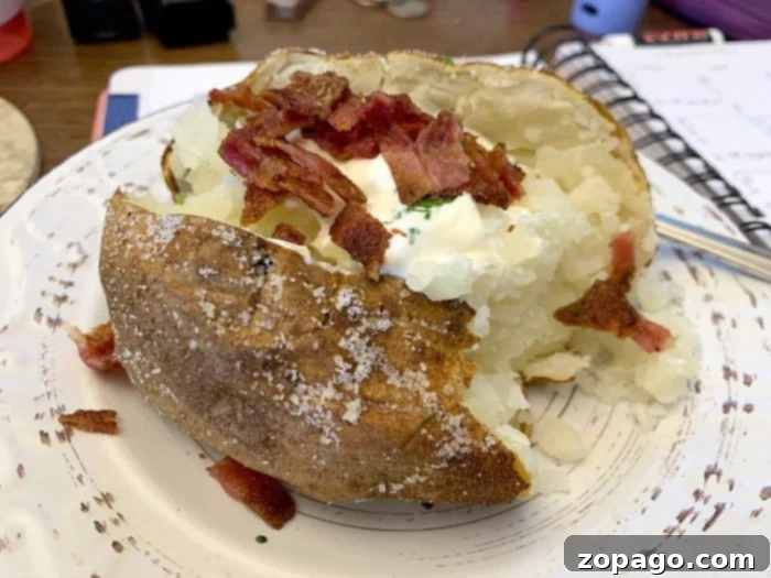 Crispy Foodi Baked Potatoes 5 Various toppings for baked potatoes displayed on a table, including cheese, sour cream, bacon bits, and fresh chives.