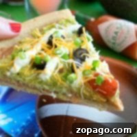The 7 layer dip pizza features a slice topped with guacamole, cheese, olives, and tomatoes served stylishly on a football-themed plate.