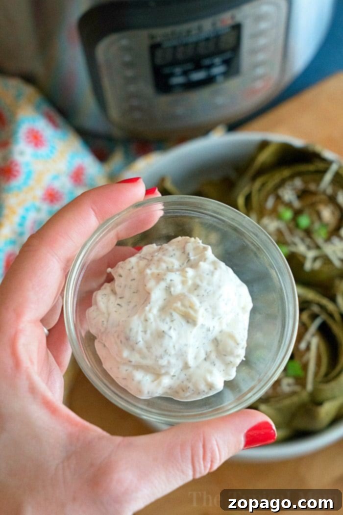 Easy Instant Pot artichokes with creamy dill dipping sauce ready in less than 15 minutes! How to steam artichokes in your pressure cooker to perfection. Our favorite vegetable for dinner and a healthy side dish too. #instantpot #pressurecooker #vegetables #artichokes #artichoke #instantpotrecipes #thetypicalmom #vegetarian Easy Instant Pot Artichokes with creamy dill dip in a bowl