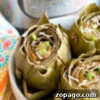 Steamed artichokes with Parmesan and green onions sit in a white bowl, freshly cooked to perfection using the Instant Pot.