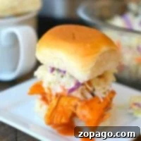 Pulled chicken sliders with coleslaw rest on a square white plate, accompanied by a mug, hinting at their tender perfection from the pressure cooker.