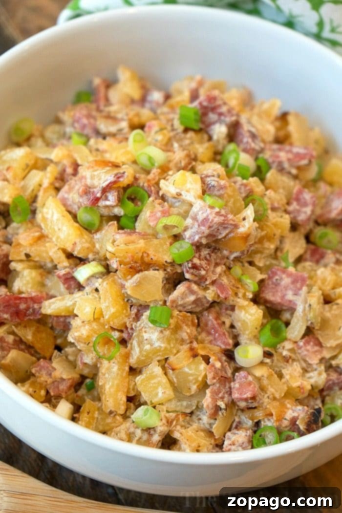 Creamy corned beef hash with green onions. A bowl of creamy classic corned beef hash, topped with chopped green onions.