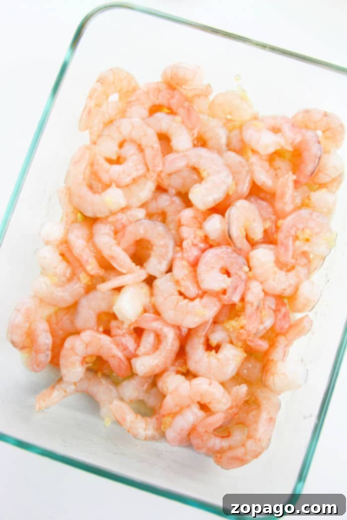 Garlic Shrimp with Zucchini Noodles 3 A glass dish filled with raw, peeled shrimp is arranged neatly, ready to transform into a zesty masterpiece.