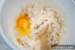 A wooden spoon mixing flour and an egg in a white bowl—perfect for starting your 3 ingredient dump cake.