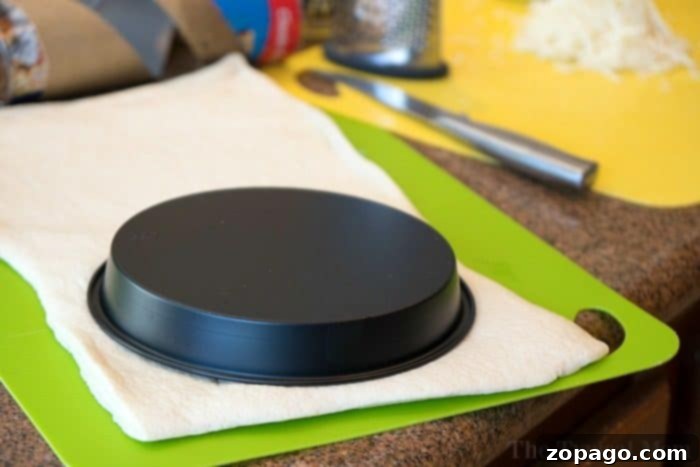 Easy Instant Pot Pizza 4 Raw pizza dough being pressed into an Instant Pot pizza pan, forming the crust for a deep dish pizza.