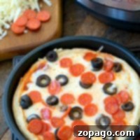 A deep-dish Instant Pot pizza, topped with pepperoni and olives, is presented in its pan, with a bowl of shredded cheese in the background.