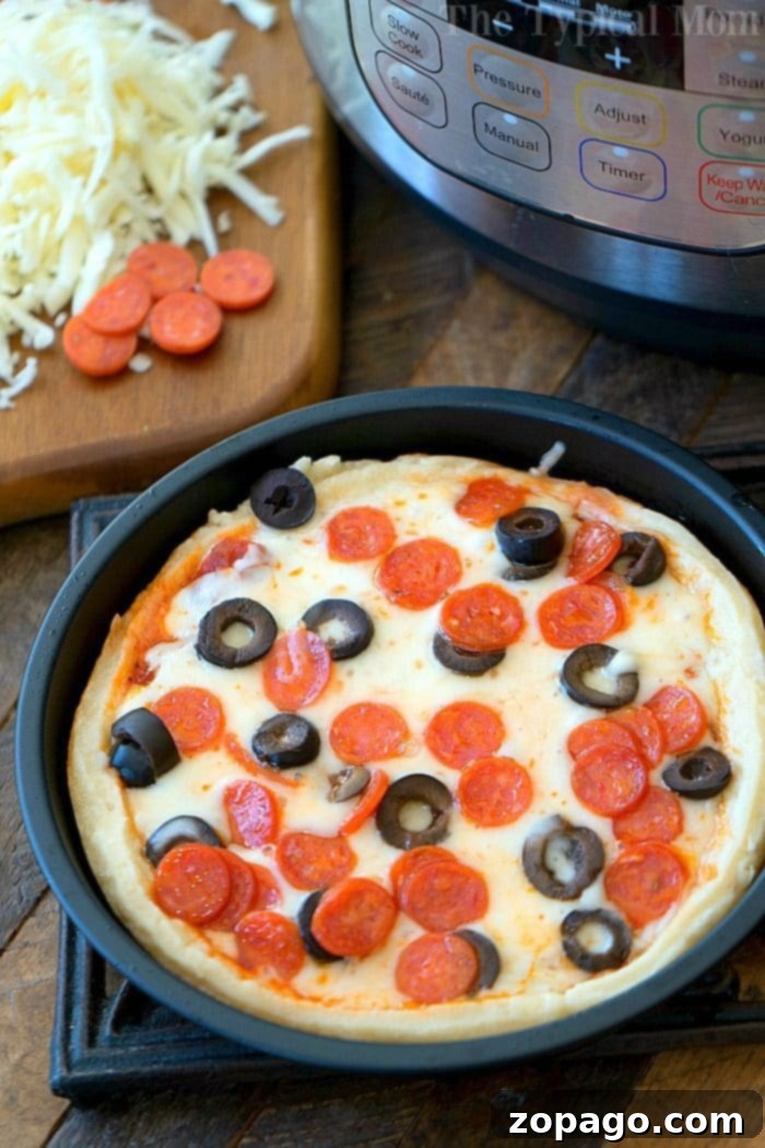 Easy Instant Pot Pizza 9 A close-up of a bubbling Instant Pot pizza, topped with melted cheese and pepperoni, highlights its deep-dish crust. A sliver of black olive is visible on one slice.