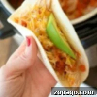 A delicious Instant Pot Salsa Chicken taco, topped with shredded cheese, fresh avocado, and diced tomatoes, a perfect quick meal.