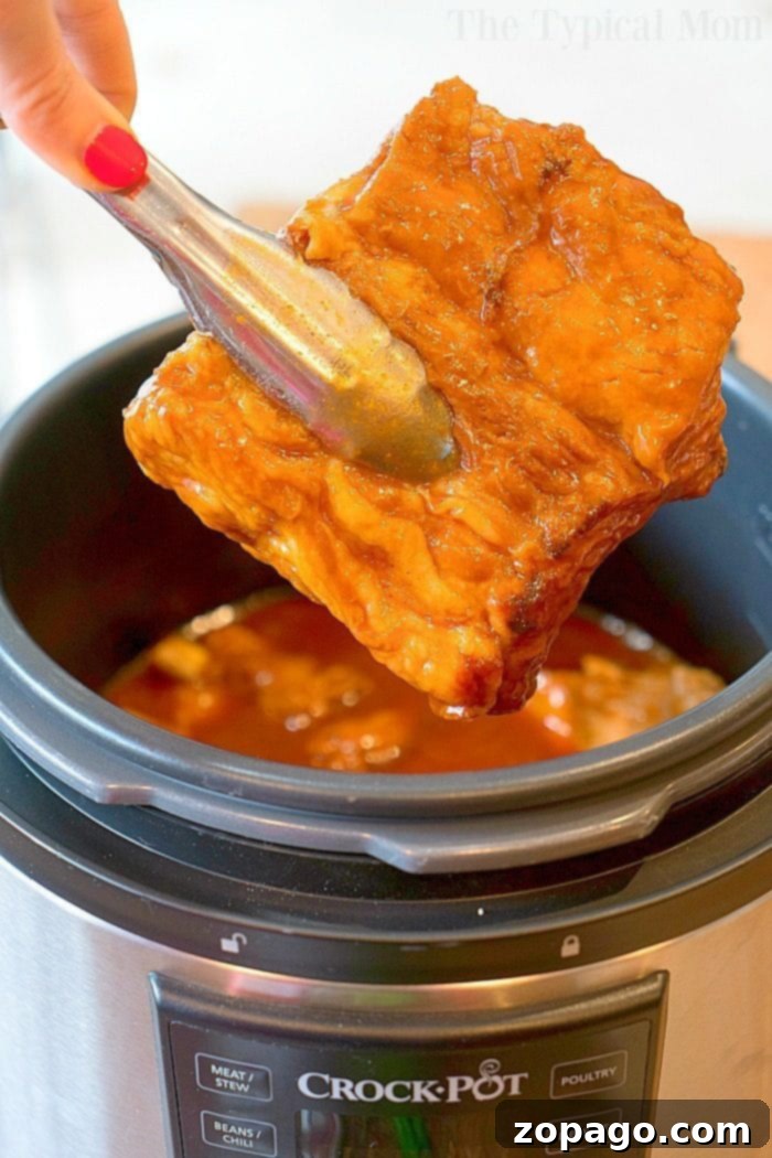 Tender Crock Pot Express Ribs 4 A close-up of glazed and tender barbecue ribs on a serving plate.