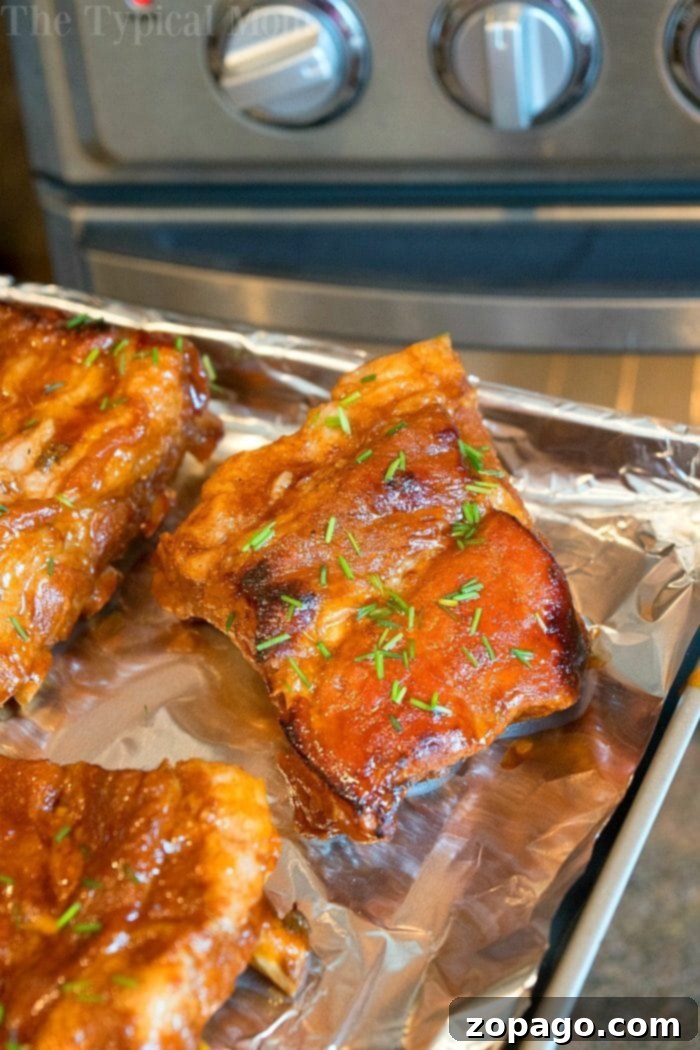 Tender Crock Pot Express Ribs 5 Close-up of a stack of delicious, glossy Crockpot Express ribs on a rustic board, garnished with fresh herbs.