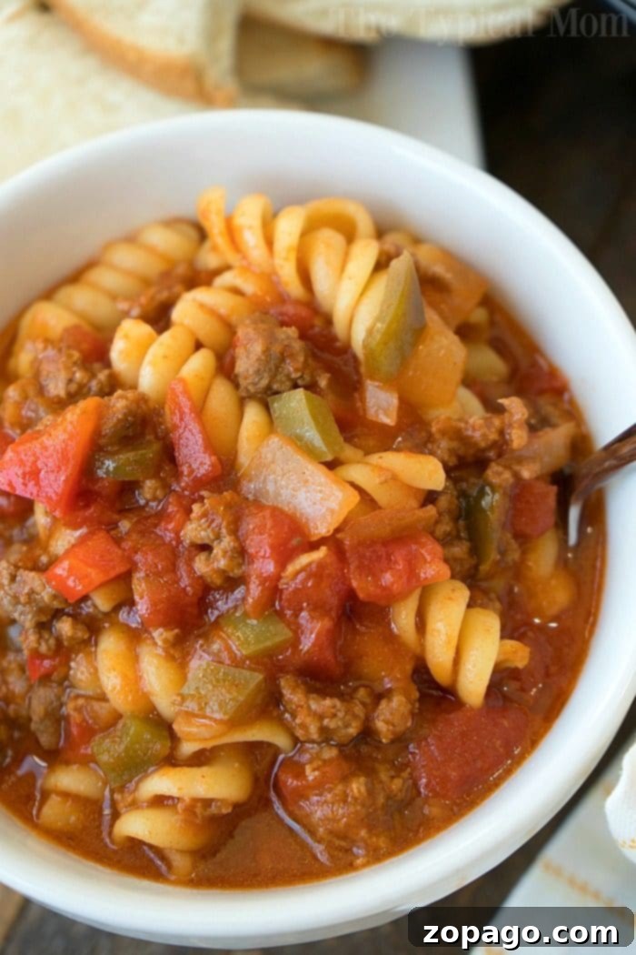 This Instant Pot sloppy joe casserole is my kids favorite dinner. All the best flavors of sloppy joe but with pasta instead of a bun and packed with flavor! A serving of Instant Pot Sloppy Joe Casserole in a bowl, showcasing the rich texture of the sauce, ground meat, and pasta, with a spoon for scooping.