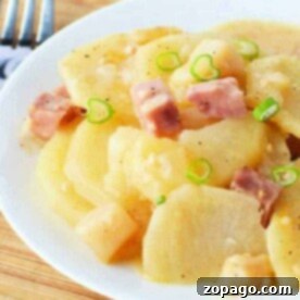 Crockpot Creamy Potato Bake 3 A plate of slow cooker scalloped potatoes topped with diced ham and green onions sits invitingly on a wooden board, accompanied by a fork.