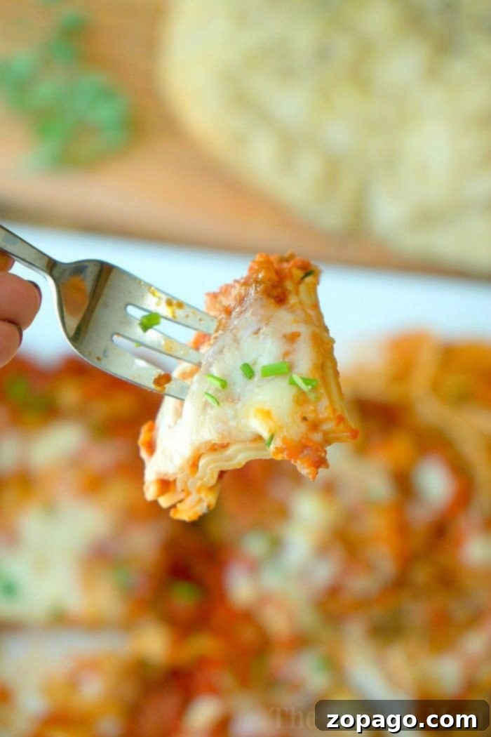 Warm & Fluffy Slow Cooker Rolls 7 A fork holding a cheesy lasagna piece, garnished with herbs, with more enchiladas and slow cooker rolls in the background.