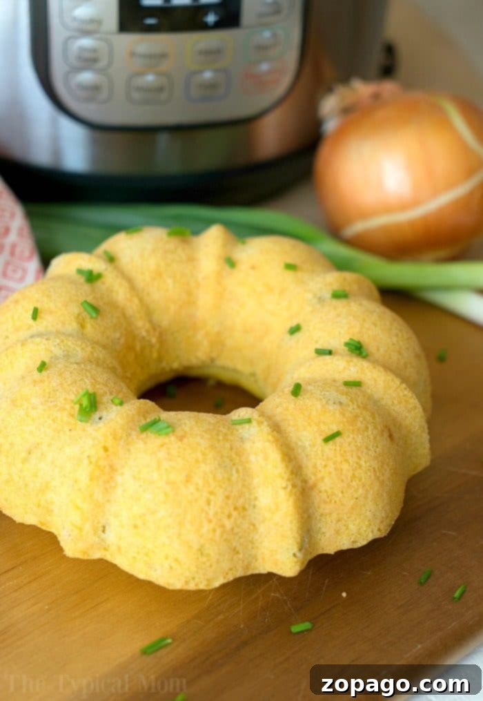 Perfectly Moist Instant Pot Cornbread 4 Delicious pressure cooker cornbread in a bundt shape, garnished with fresh chives, on a rustic wooden board. Accompanied by green onions and a patterned cloth, hinting at a warm, savory meal.