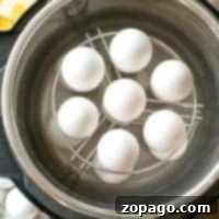 White eggs neatly arranged on a metal rack inside an Instant Pot, the perfect setup for making hard-boiled eggs effortlessly.