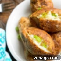 The best way to make baked potatoes is to serve them topped with chopped green onions on a white plate, resting perfectly on a wooden table.