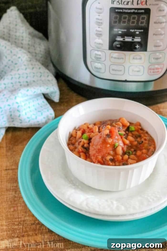 Easy Instant Pot Black Eyed Peas and Ham: A Hearty, No-Soak Recipe for Pressure Cooker, Crockpot, or Slow Cooker, perfect for using leftover ham after the holidays. Healthy and delicious comfort food. A white bowl of bean stew sits on plates in front of an Instant Pot, featuring hearty pressure cooker black eyed peas and ham, on a wooden surface. Garnished with fresh green onions for a pop of color.